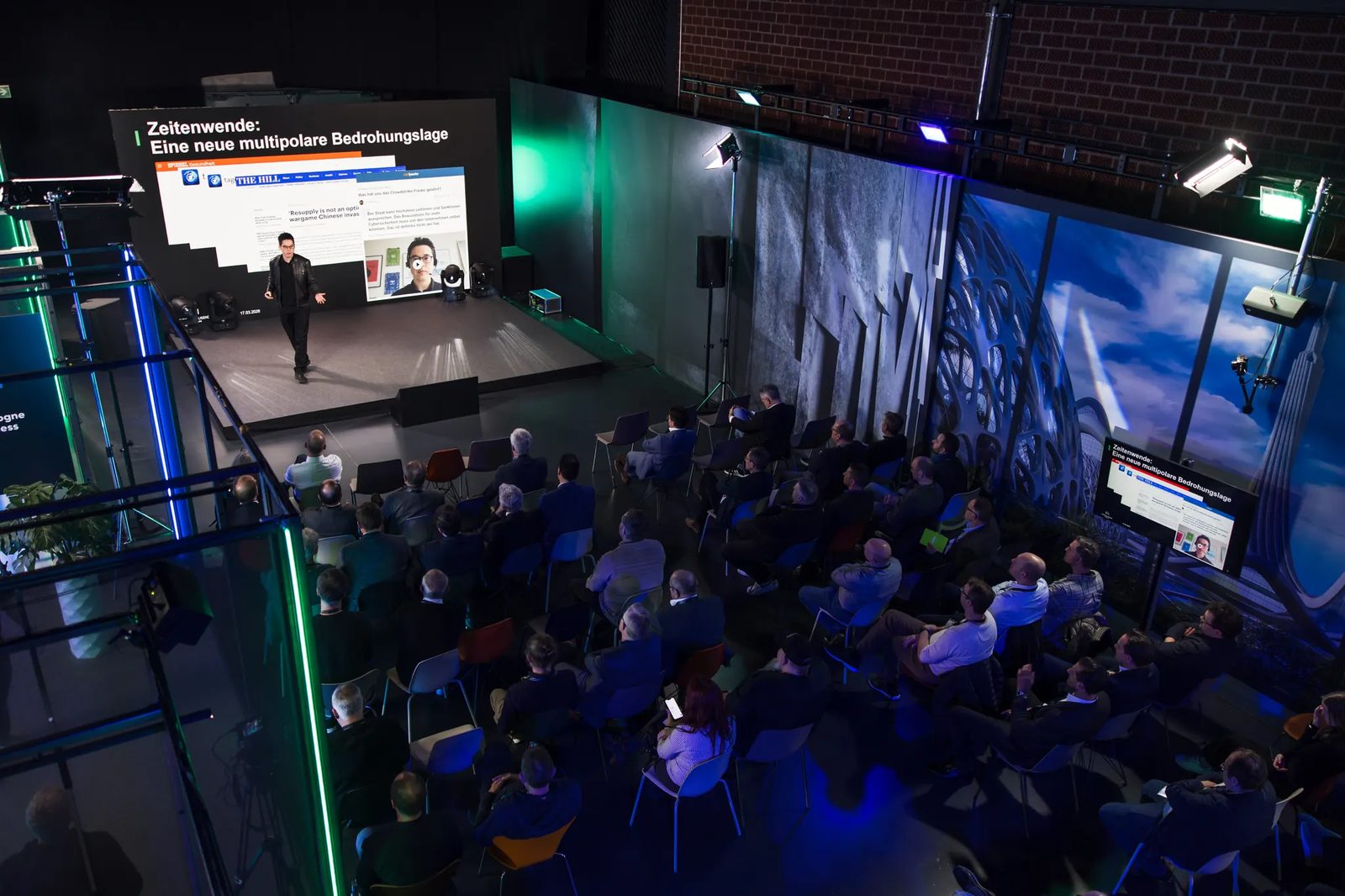Keynote im Neyroo Studio von oben: Bühne mit LED-Wall, zugeschalteter Speaker, voll besetzte Reihen